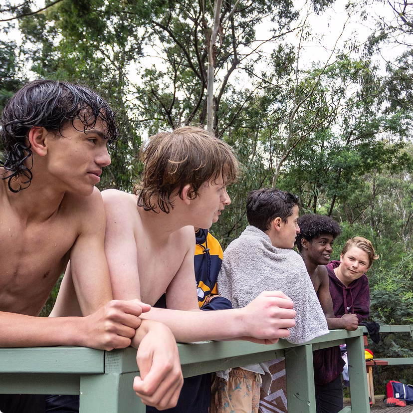 Australian teens outside, at a lake, standing together and looking over the railing.