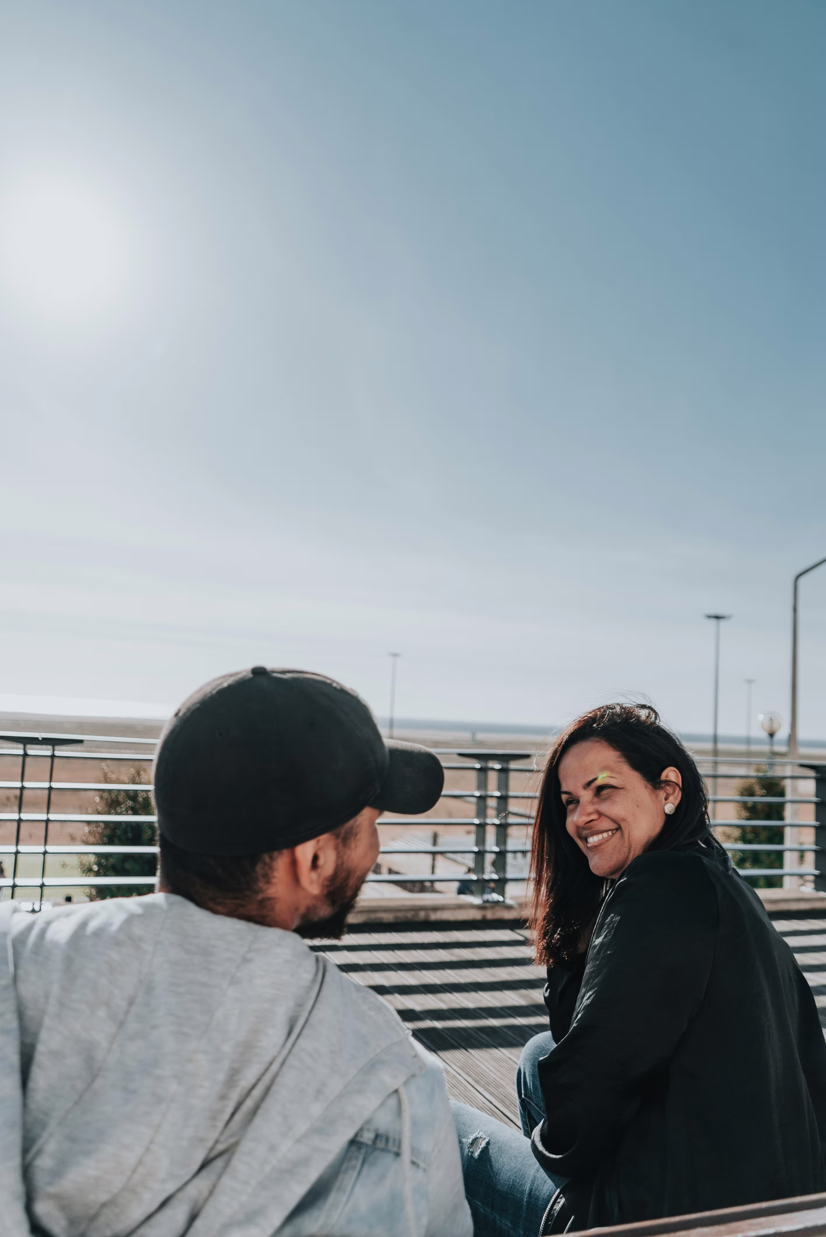 A woman smiling warmly during a conversation with a man outdoors.