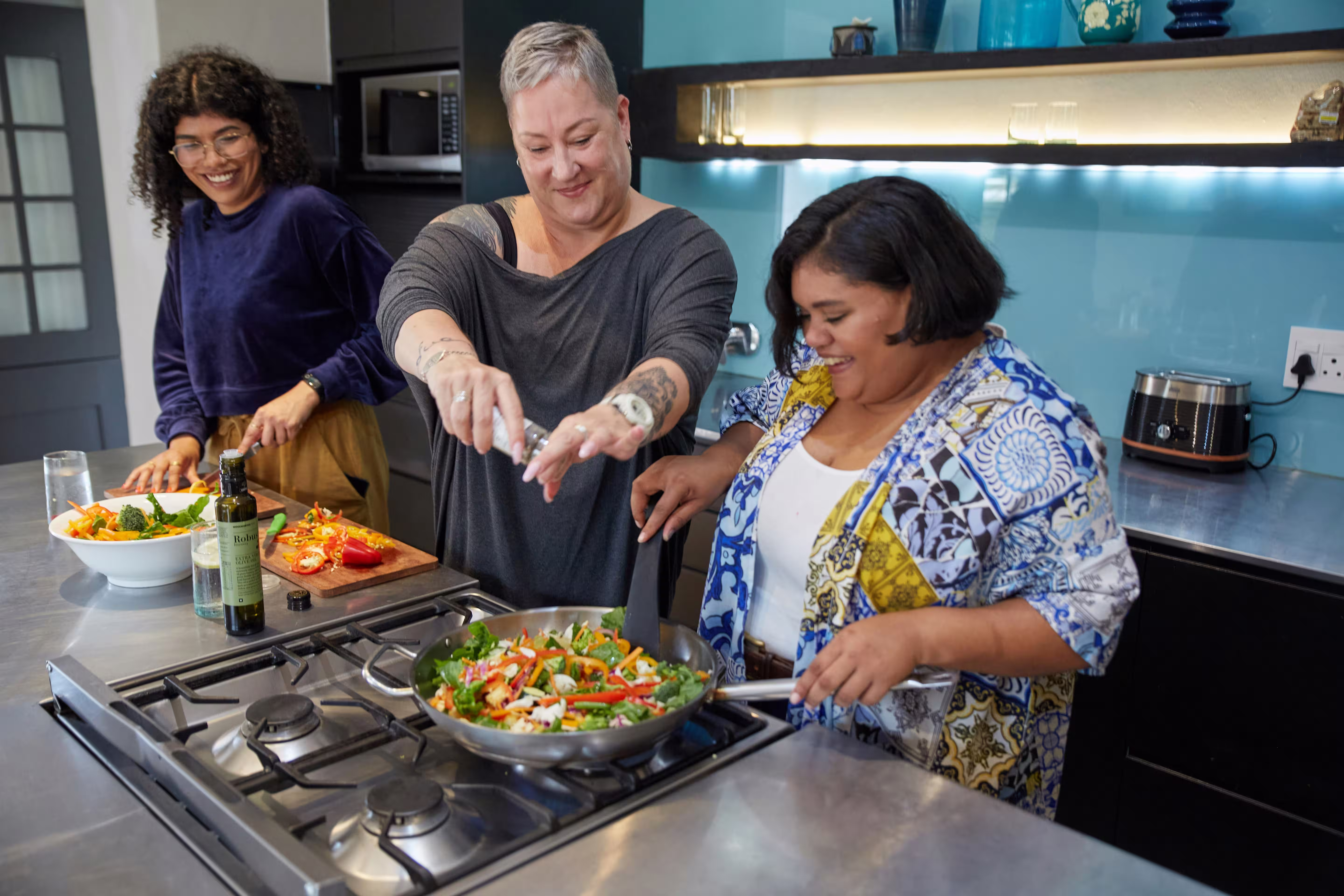 Three women cooking a meal together in a kitchen.