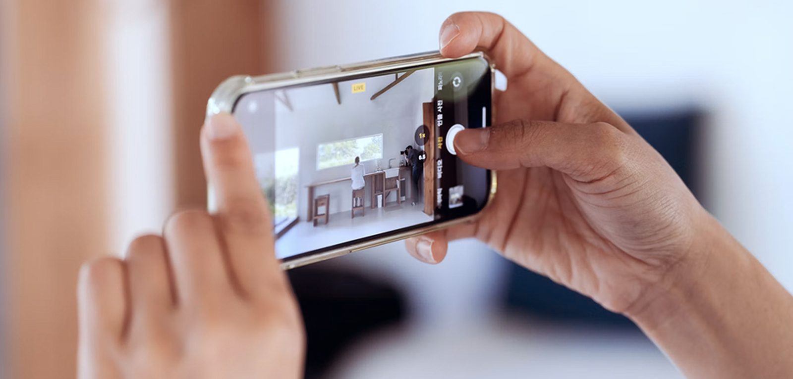 A person's hands holding a smartphone, with the screen showing a live view of a room interior.